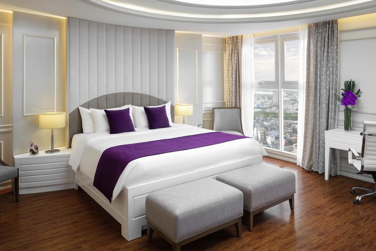 Een moderne hotelkamer met een groot bed, een bureau en uitzicht op de stad.