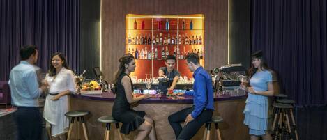 A bar area with stools, a bartender, and a well-stocked shelf of bottles.