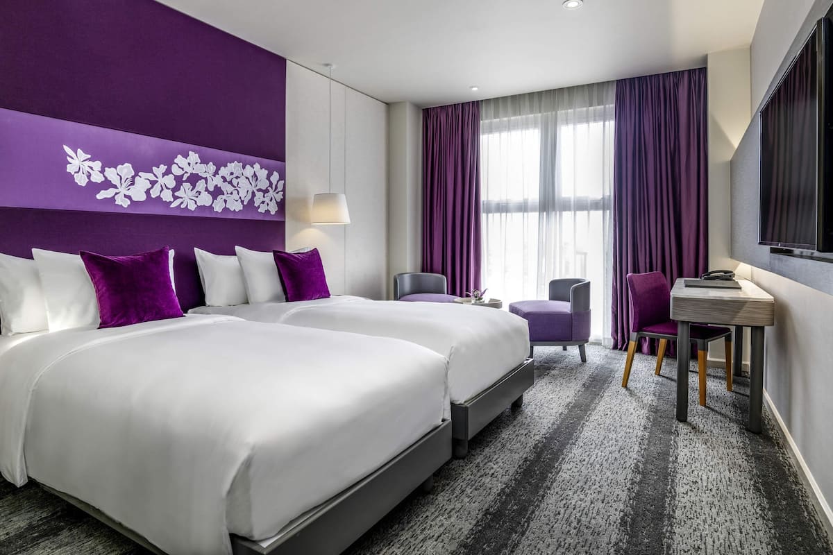 Een hotelkamer met twee bedden, een bureau, een stoel en een televisie.