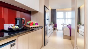 A modern hotel room with a kitchen area, a dining table, and a bed with a view. - Mercure Hai Phong (Hai Phong)