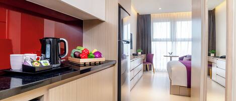 Una habitación de hotel moderna con cocina, una mesa de comedor y una cama con vistas.