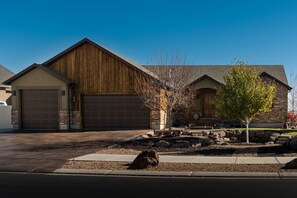 A residential building with a garage, a stone facade, and a landscaped front yard with a tree and rocks. - Within Minutes Of BYU, Temples, Skiing Sleeps 18 (Vineyard)
