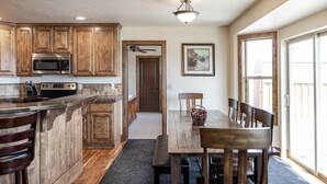 A kitchen with wooden cabinets, a microwave, a stove, and a dining area with a table and chairs. - Within Minutes Of BYU, Temples, Skiing  Sleeps 18 (Vineyard)