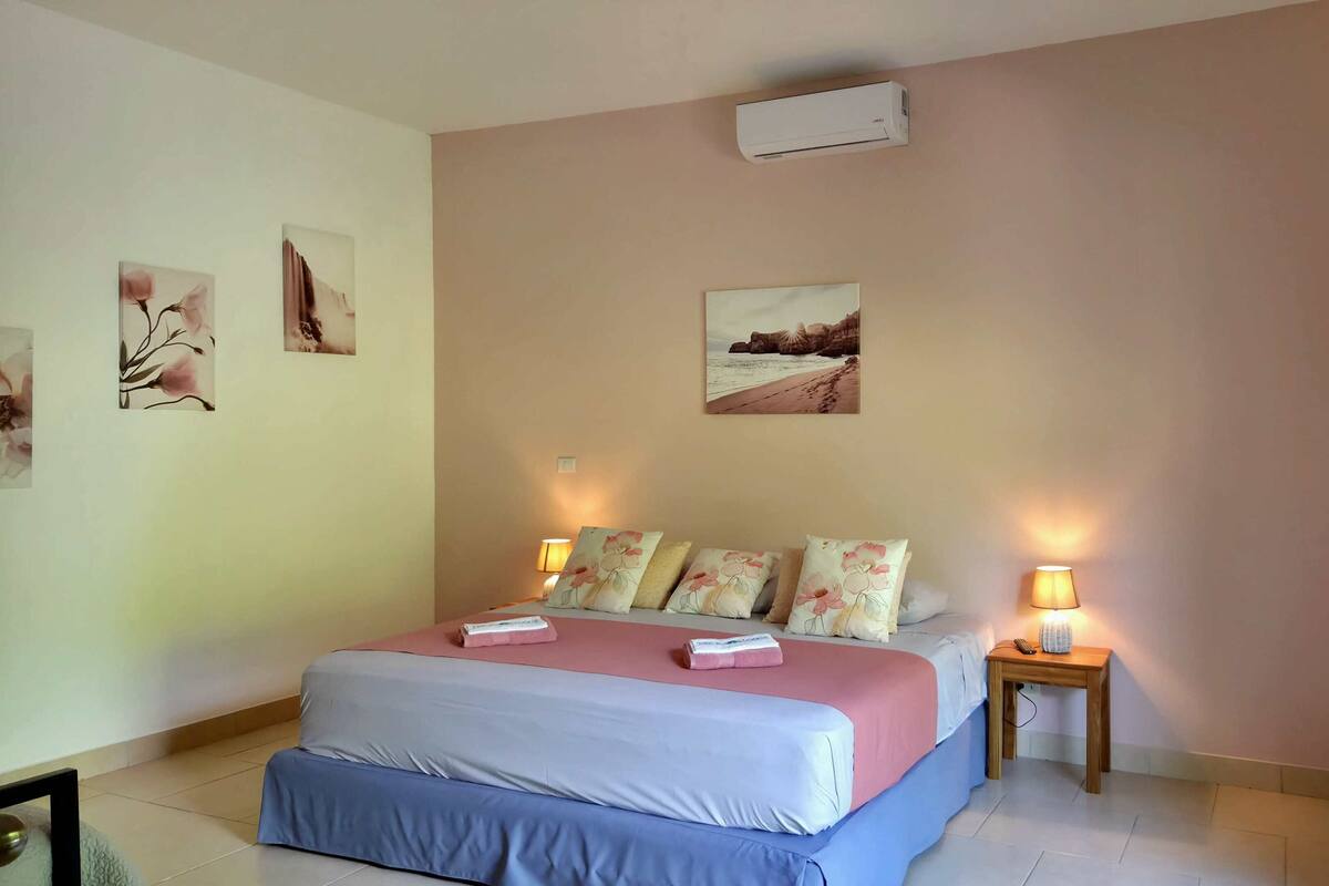 Un dormitorio con cama, dos lámparas de noche, una mesita de noche y decoración en la pared.