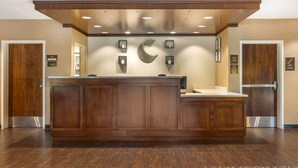 Un área de recepción con un mostrador de madera, un gran logotipo C fijado a la pared e iluminación empotrada en el techo.