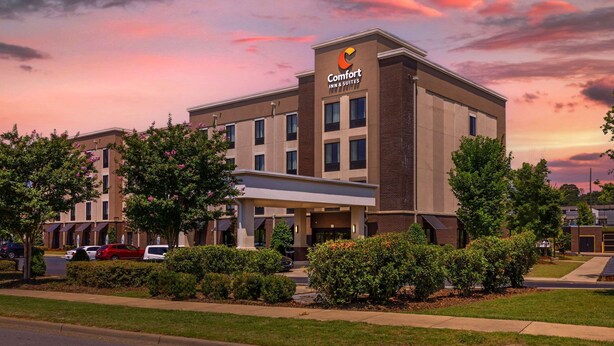 Un hotel Comfort Inn & Suites con diseño moderno, que destaca por su entrada principal y zona de estacionamiento.