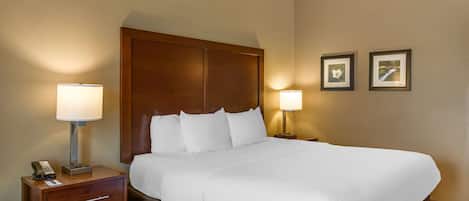 Ein Hotelzimmer mit einem großen Bett, zwei Nachttischlampen, einem Nachttisch aus Holz mit einem Telefon und zwei gerahmten Bildern an der Wand.