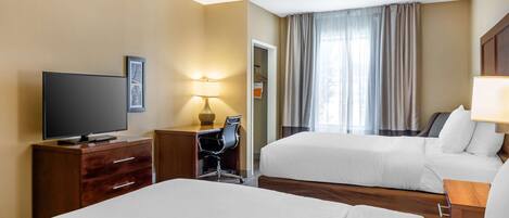 A hotel room with two beds, a desk with a TV, a chair, a lamp, and a wardrobe.