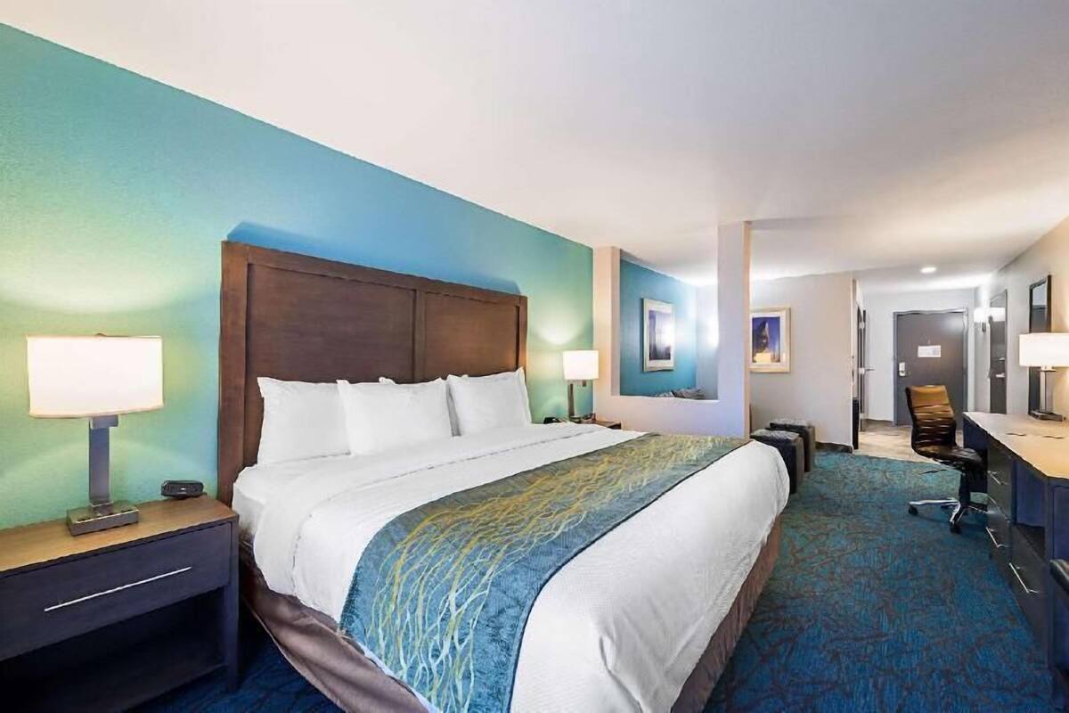 Ein Hotelzimmer mit einem großen Bett, Nachttischen, einem Schreibtisch und einem Sessel.