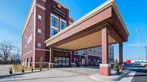 Egy tégla homlokzatú, nagy ablakokkal és fedett bejárati előtérrel rendelkező Comfort Inn & Suites szálloda.