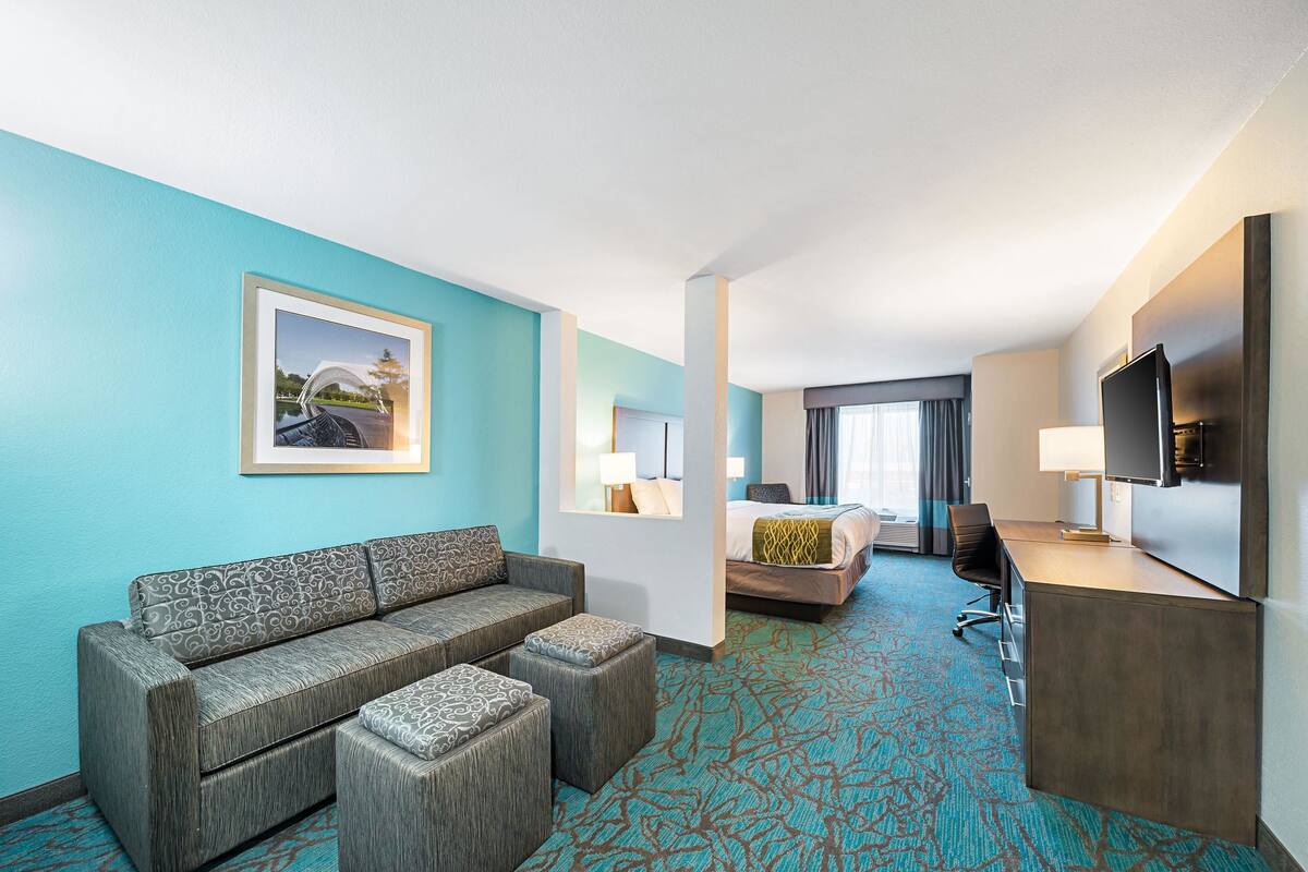 Ein Hotelzimmer mit einer Couch, einem Bett, einem Schreibtisch und einem Fernseher.