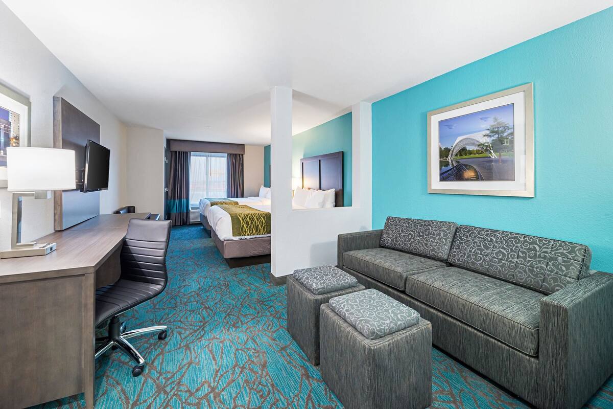 Ein Hotelzimmer mit einem Bett, einer Couch, einem Schreibtisch mit Stuhl und einem Fernseher.