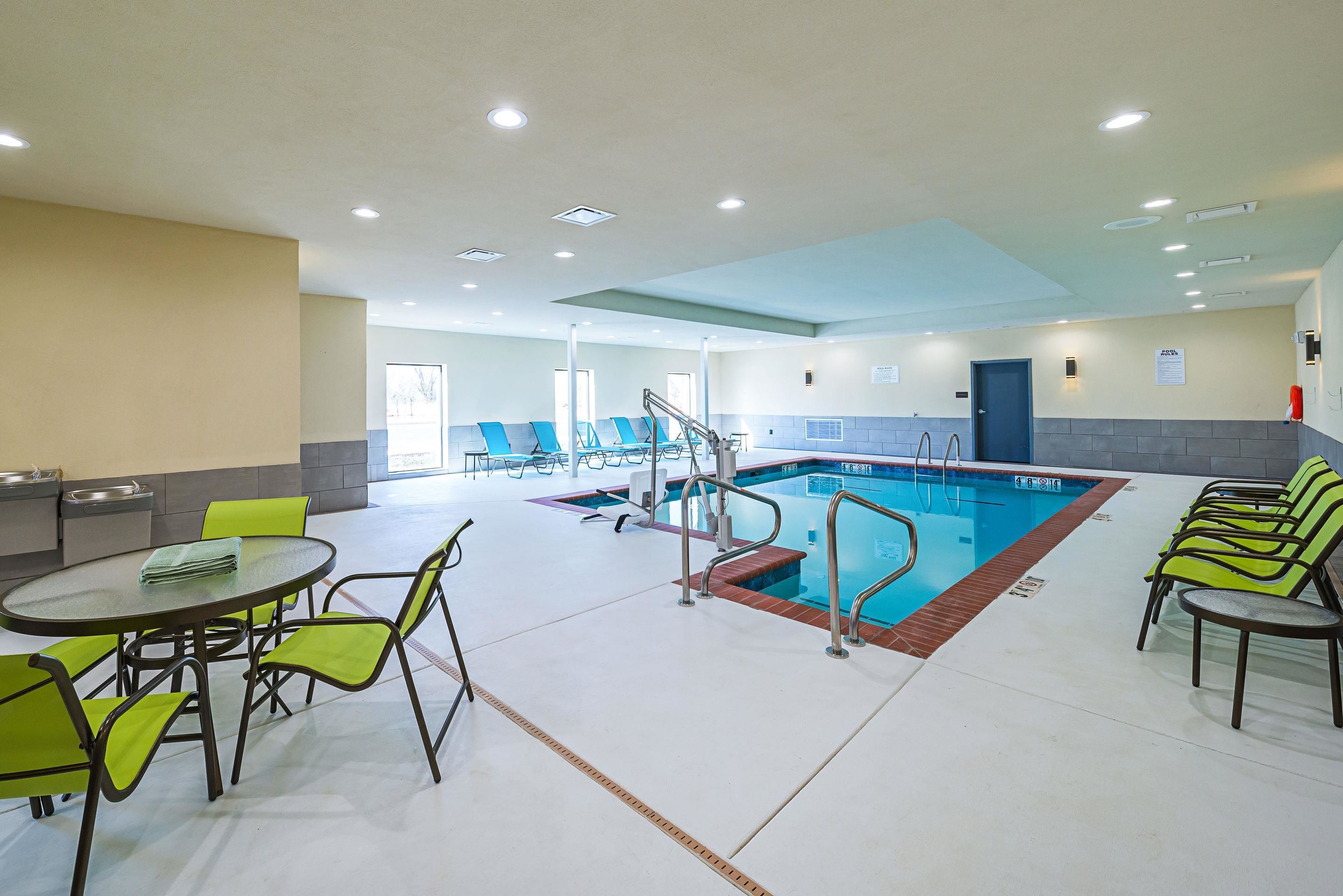Zona de piscina con piscina, sillas y una mesa.