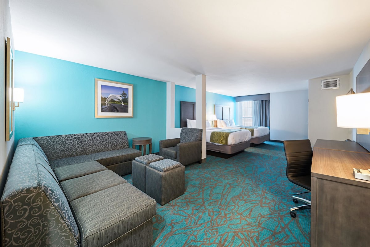 Ein Hotelzimmer mit einer großen Couch, einem Bett, einem Schreibtisch und einem kleinen Tisch.