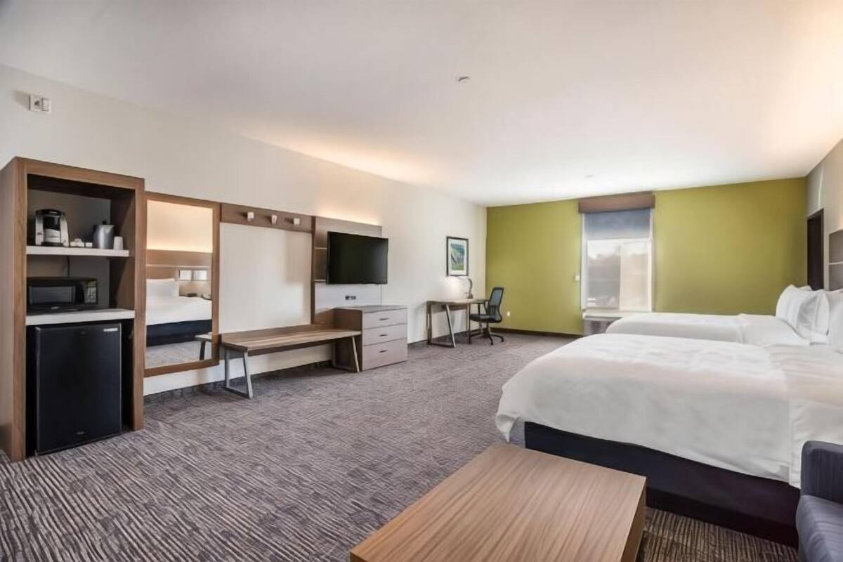 A hotel room with a bed, desk, chair, television, and a small refrigerator.