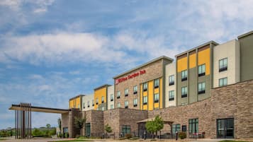A modern hotel with a stone facade, multiple floors, and a prominent 'Hilton Garden Inn' sign.