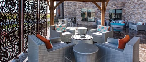 Eine Terrasse im Freien mit Korbmöbeln, einem runden Tisch und einer Backsteinwand.
