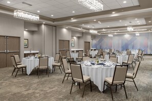 Une salle de conférence avec des tables rondes, des chaises et des lustres.