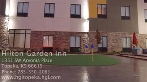 Un Hilton Garden Inn con fachada de ladrillo, varias ventanas y un césped.