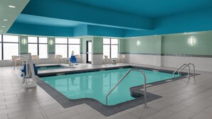An indoor swimming pool with clear water, a diving board, and a changing room area. - Hilton Garden Inn Topeka (Topeka)