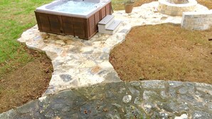 Un bain à remous avec une terrasse en pierre, un foyer et un mur en pierre.