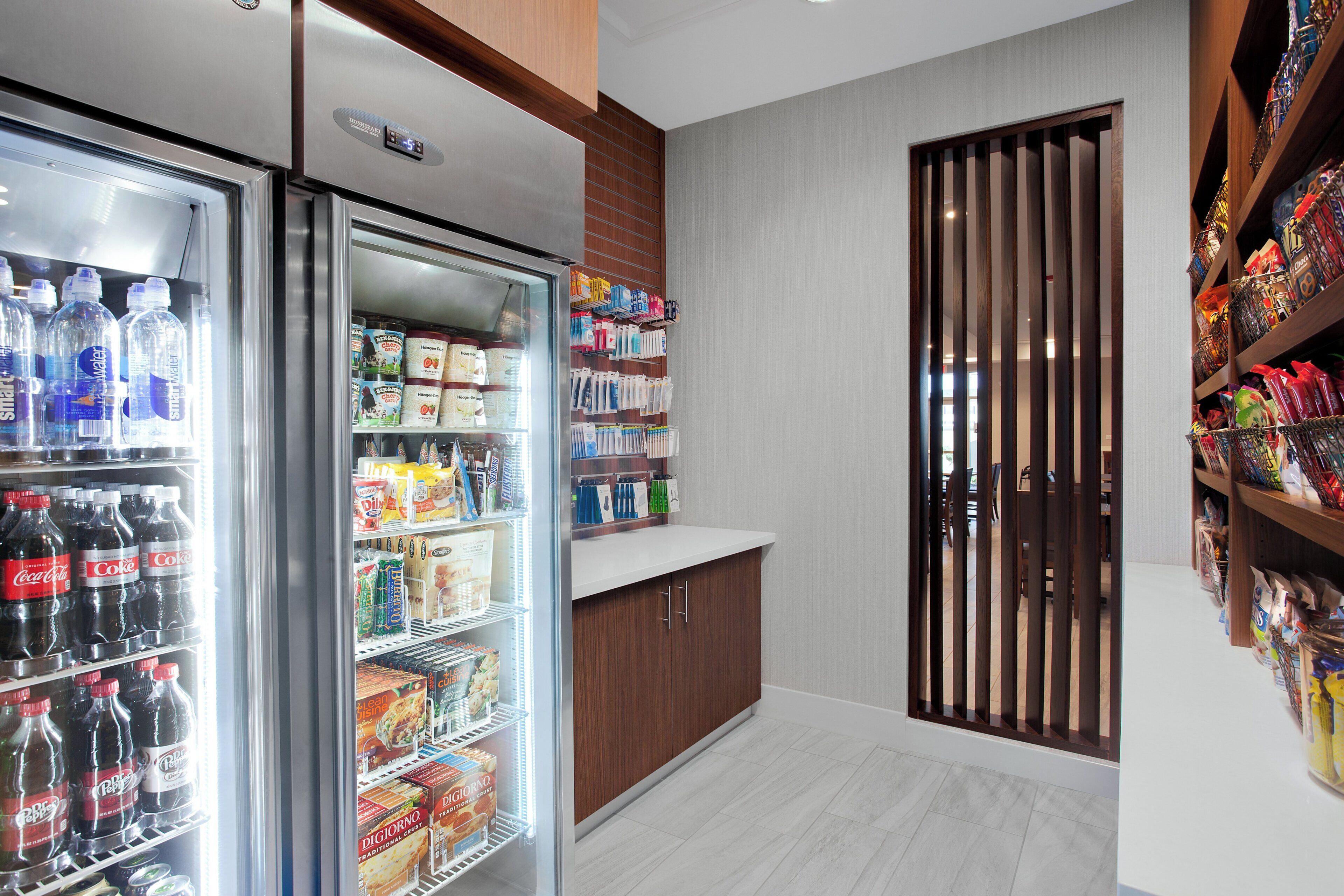 A kitchenette with a refrigerator stocked with beverages, a microwave, and a coffee machine.