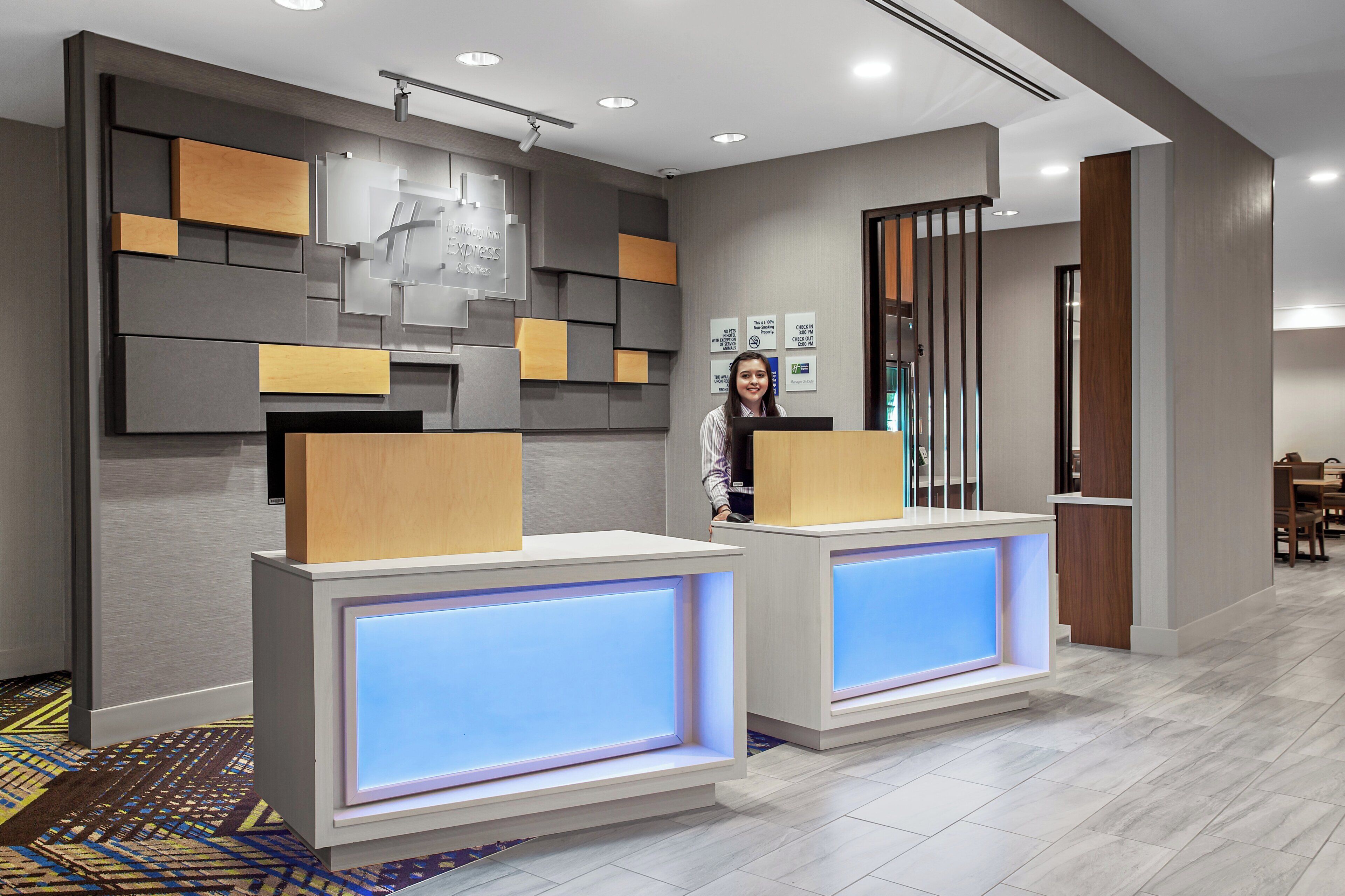 A reception area with a modern design, featuring a reception desk, a wall-mounted information board, and a patterned carpet.