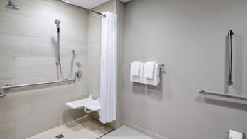 A modern bathroom with a shower, grab bars, a toilet, and a towel rack.