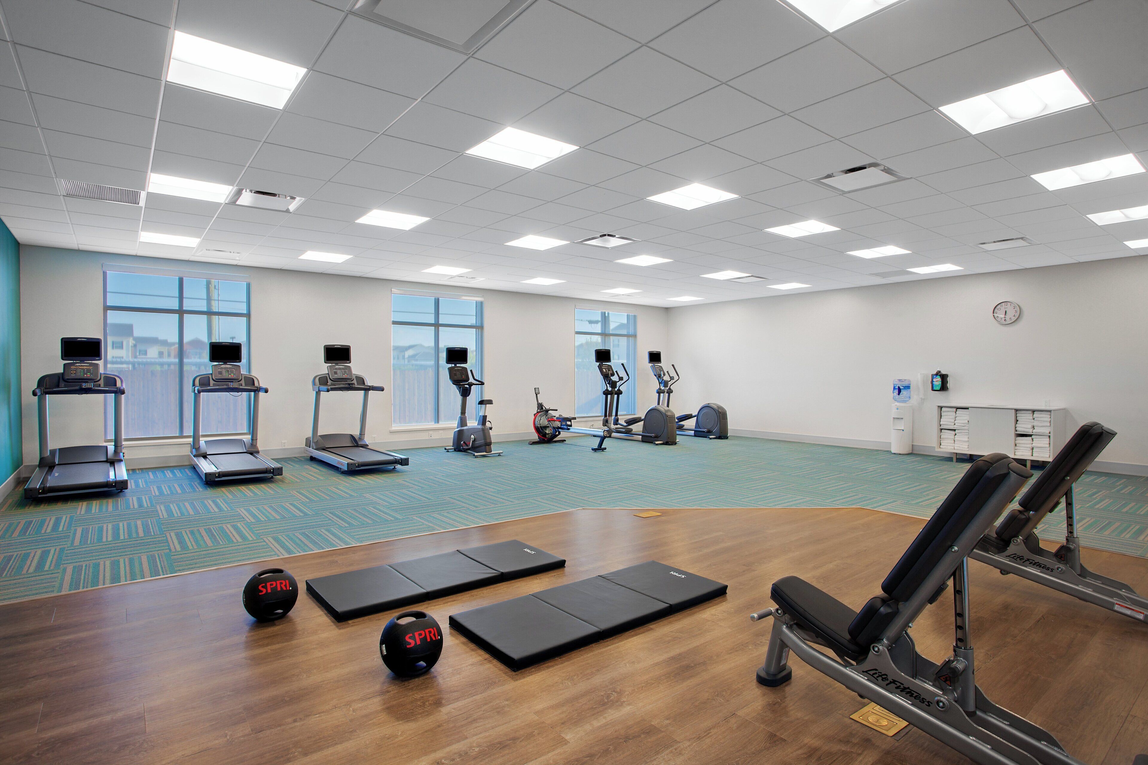 Ein Fitnessraum mit Laufbändern, einem Crosstrainer, einem Rudergerät und einer Liegebank.