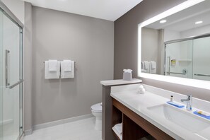 A modern bathroom with a glass shower enclosure, a white sink with a mirror, and two white towels on the wall. - Holiday Inn Express & Suites Lubbock Central - Univ Area by IHG (Lubbock)