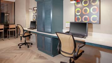 Een moderne kantoorruimte met twee bureaus, stoelen en een grote kast.