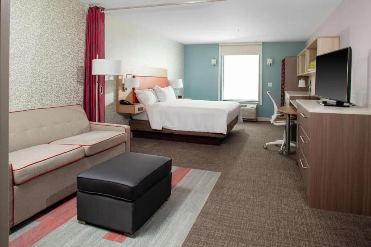 Una habitación de hotel con cama, sofá, escritorio y televisor.
