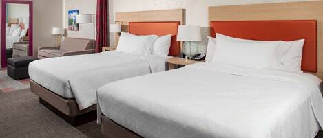 A hotel room with two beds, a sitting area, and a mirror.