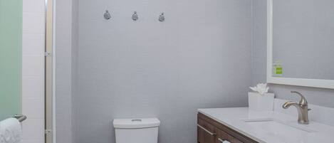 A bathroom with a toilet, sink, and mirror. There are towels hanging on the wall and a towel rack.