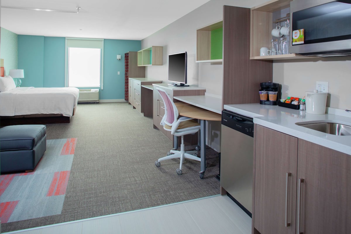 Una habitación de hotel moderna con cama, escritorio y kitchenette.