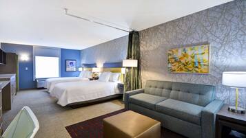A hotel room with two beds, a sofa, a desk, and a large window.