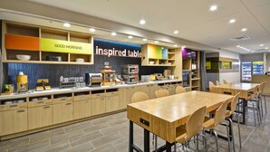 Una cafetería moderna con muebles de madera, una estación de café de autoservicio y un letrero que dice 'Good Morning'.