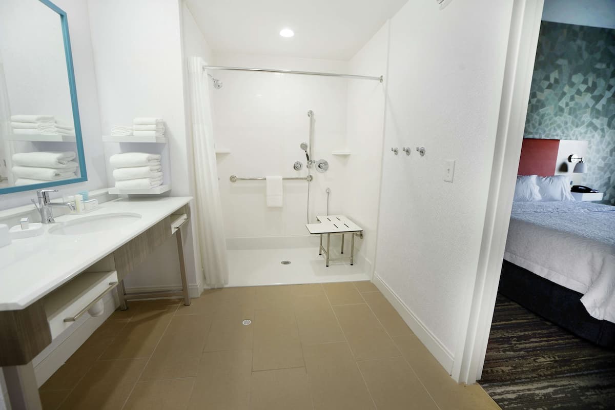 Een moderne badkamer met een douche, wastafel en spiegel.