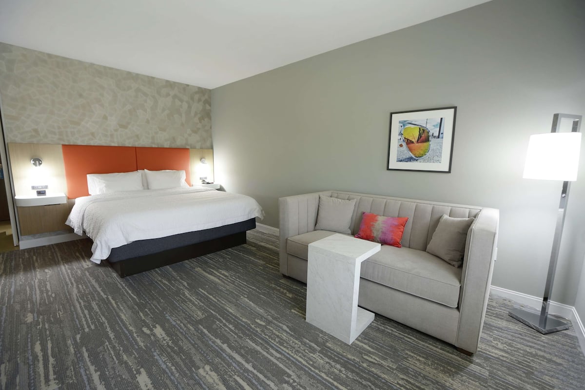 Een hotelkamer met een bed, een bank, een tafeltje en een aan de muur hangend schilderij.