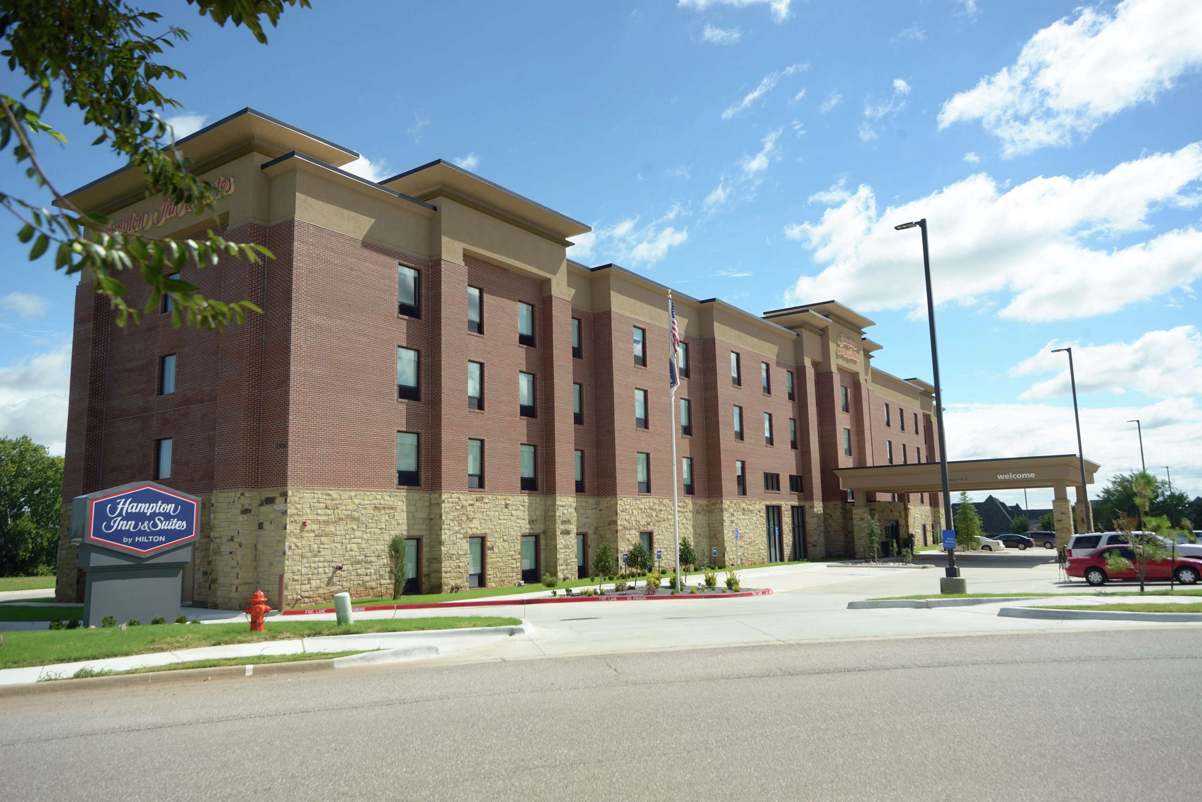 A Hampton Inn & Suites by Hilton building with a brick facade, multiple windows, and a welcoming entrance.