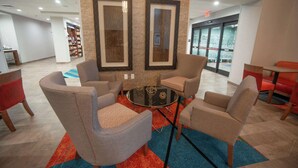 A modern lounge area with a round table surrounded by four chairs, a bookshelf, and framed artwork on the walls. - Hampton Inn & Suites Oklahoma City/Quail Springs (Oklahoma City)