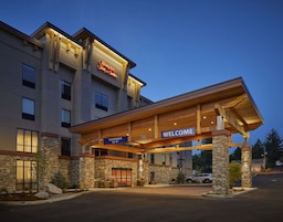 Um Hampton Inn & Suites com um letreiro 'WELCOME', fachada de pedra e entrada coberta.