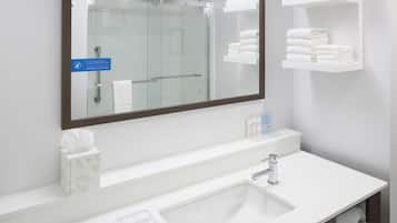 Un baño moderno con un espejo grande, lavabo blanco y espacio para toallas.