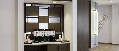 A modern kitchen with built-in coffee machines, a refrigerator, and a wooden floor.