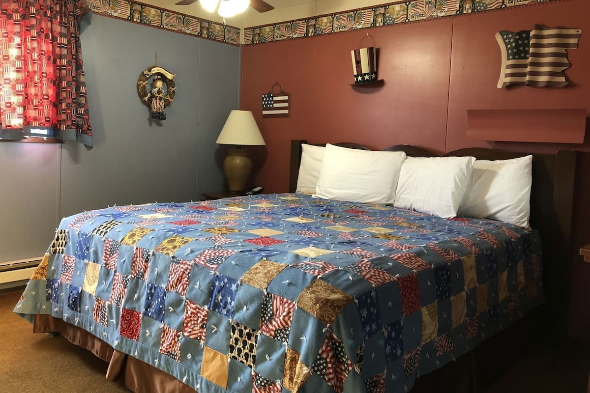 A bedroom with a large bed, a ceiling fan, a wall clock, and a flag decoration.
