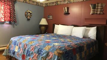 A bedroom with a bed, a ceiling fan, a lamp, and a wall with American flag decorations.