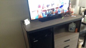 Ein Fernseher auf einem Holzständer mit einem kleinen, schwarzen Schrank darunter.