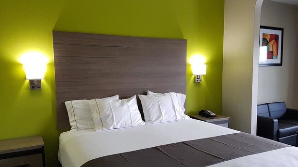 Ein Hotelzimmer mit einem Bett, zwei Nachttischen, einem Sessel und einem Bild an der Wand.