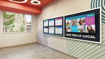Et hotel lobby med en stor digital skærm, der reklamerer for lokale attraktioner, og en slogan 'LIVE TRULY LOCAL'.