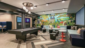 A modern lounge area with a pool table, comfortable seating, and a colorful mural.